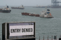Billboard reads EU SANCTIONS TIGHTEN ON RUSSIAN OIL EXPORTS with tankers in the background.